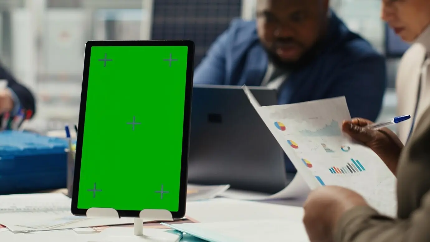 Industrial plant manager typing on a laptop with a green screen