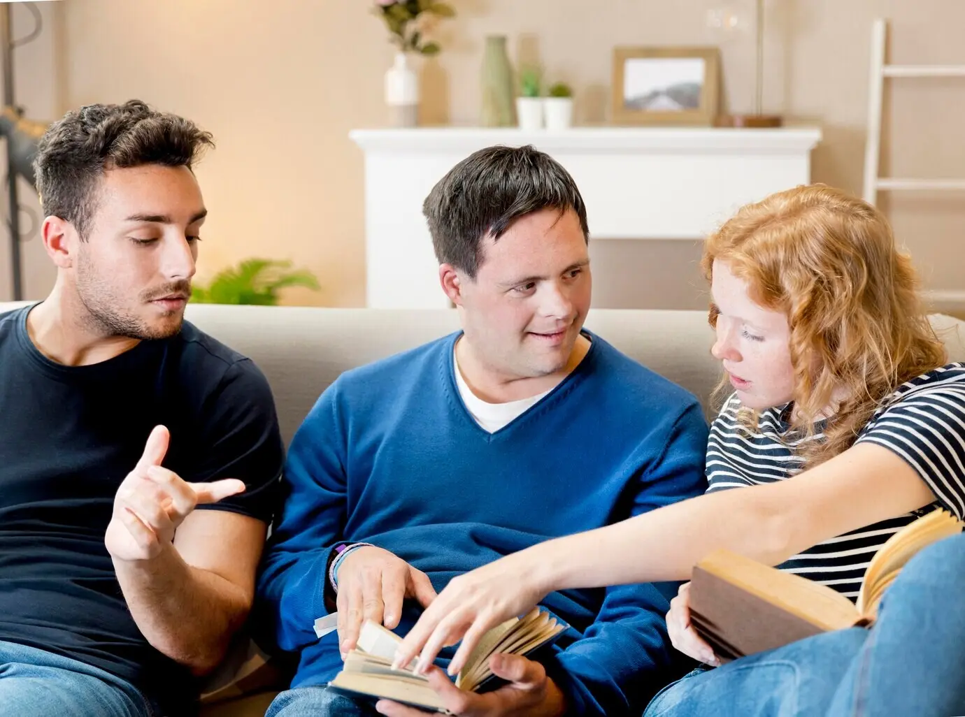 Three friends reading on a sofa at home, viewed from the front.