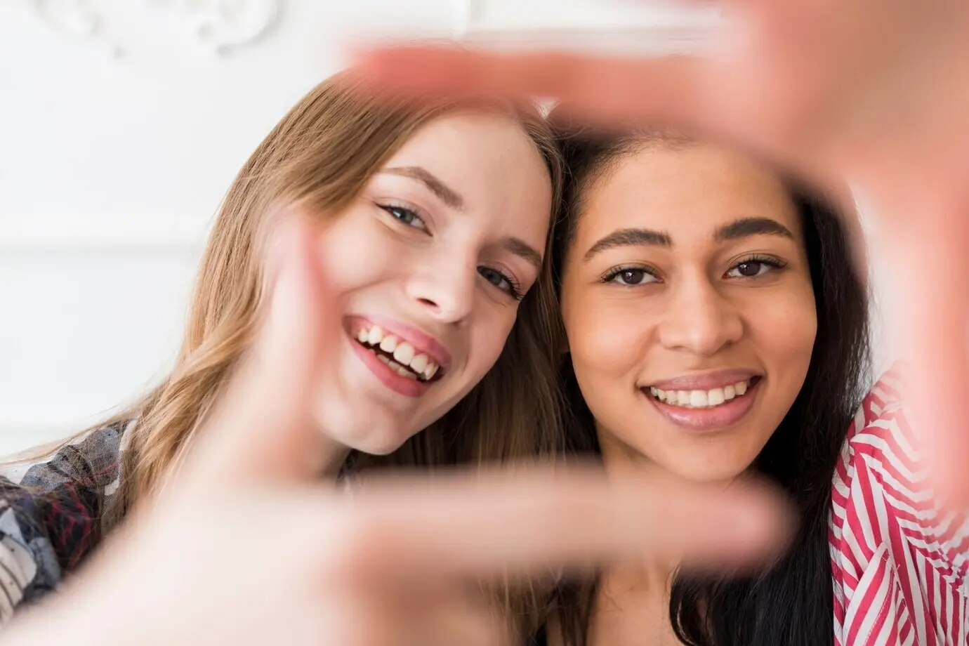 Female friends gesturing for a selfie at the camera.
